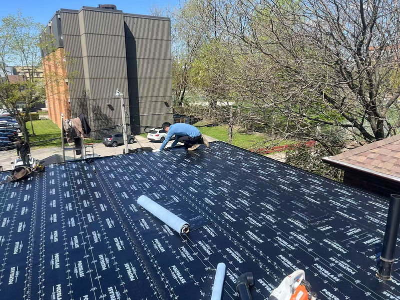 Professional roofing crew installing a Polyglass flat roof membrane on a building in Toronto.