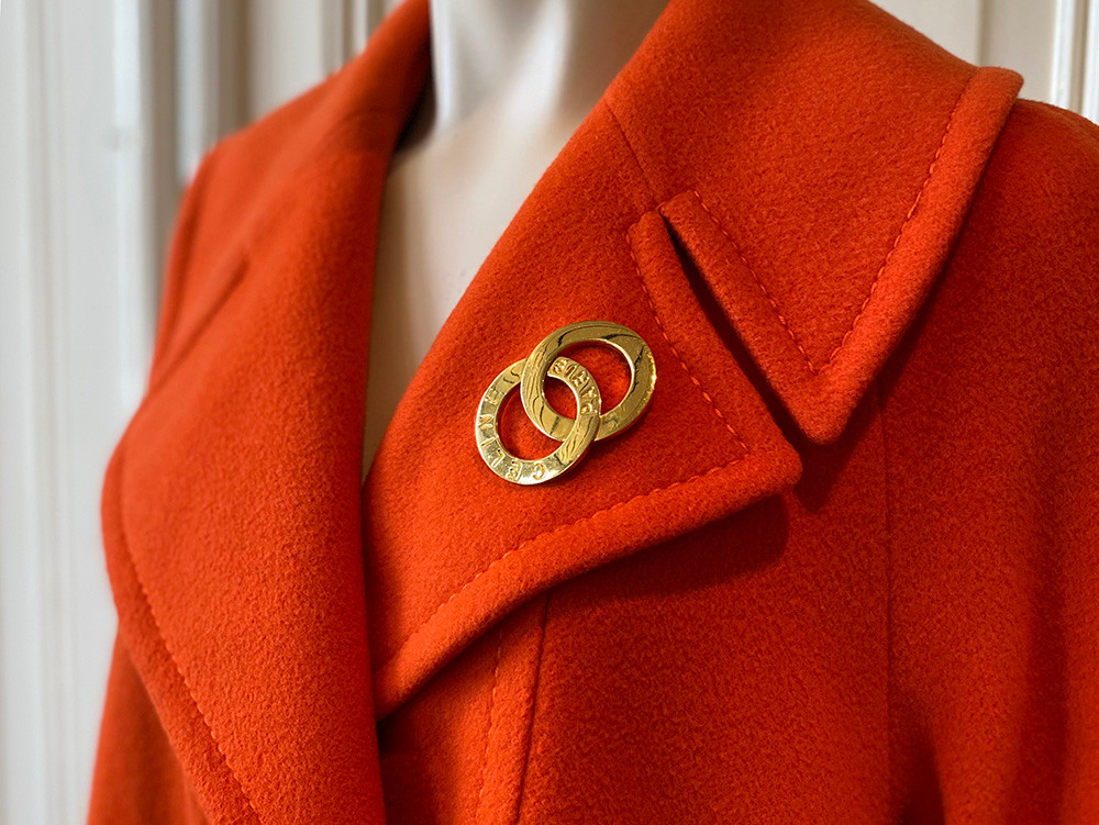 Celine broche op revers van een oranje vintage wollen mantel