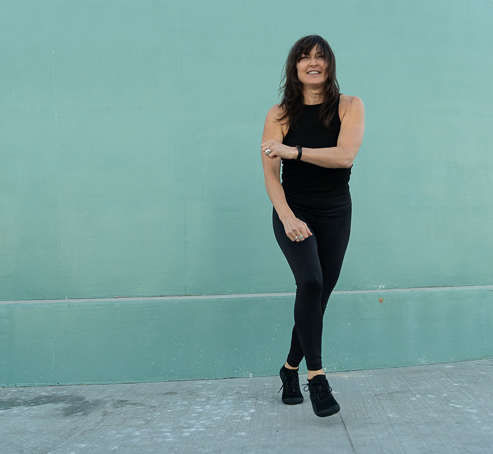 Women wearing black active wear with a teal background behind her