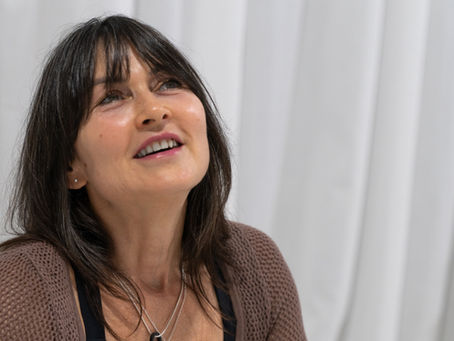 Woman dressed in a brown top and black leggings sitting on a white rug