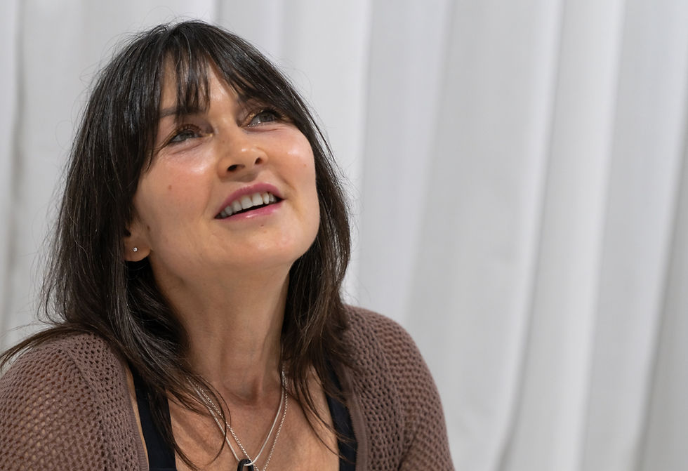 Woman dressed in a brown top and black leggings sitting on a white rug