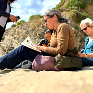 Skool students sitting on a beach, sketching.