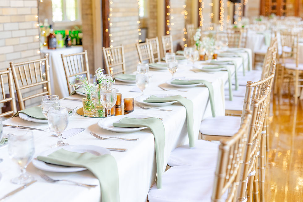Elegant banquet setup with white tablecloths, green napkins, gold chairs, and floral decor. Warm lighting creates a festive atmosphere.