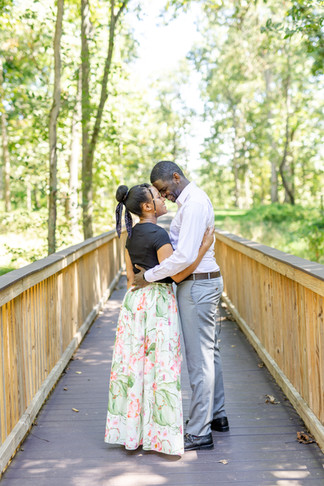 Couple looking at each other in front of trees, in a park