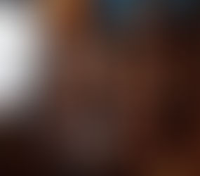 Illustration of a woman in a dimly lit loft, silhouetted against a glowing monitor displaying erotic videos including interracial and lesbian scenes, surrounded by flickering candles in a sensual, brick-walled space.