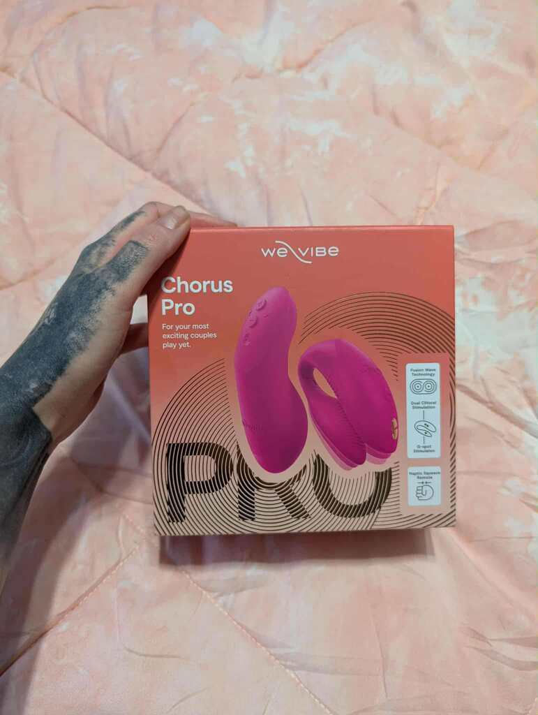 We Vibe Chorus Pro couples vibrator on silk background with soft pink and purple lighting
