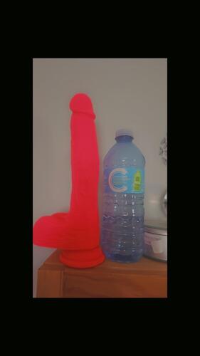 pink thrusting dildo next to a bottle of water to show girth and length