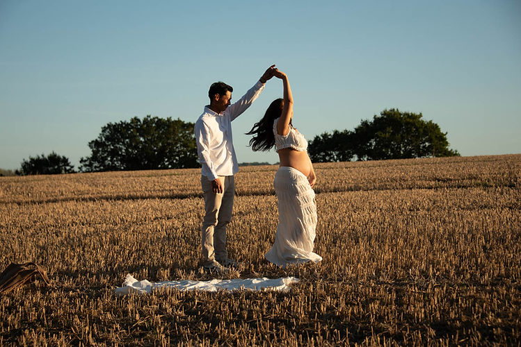 pregnant couple dancing in the fields at golden hour