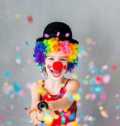 Let's party!! Funny kid clown playing at home. Child shooting party popper confetti. 1 Apr