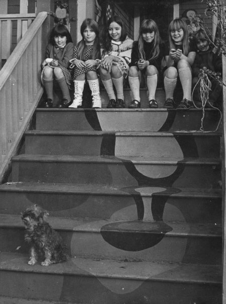 Children sit on the stairs to "Caustic Merriment" house