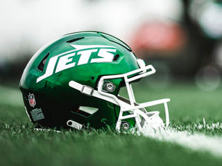 Foto de um capacete do New York Jets no gramado de um estádio