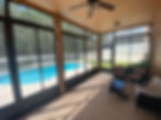 Covered and screened patio off the back of a Florida home, with swimming pool and woods visible beyond the screens