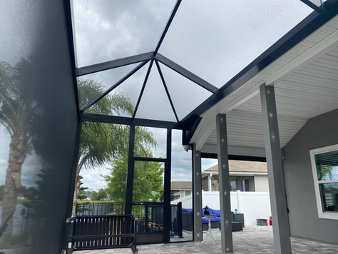 An aluminum screen enclosure meets the lanai roof at the back of a Florida house.