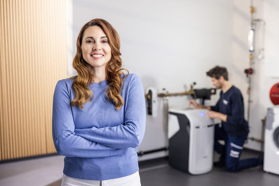 Mujer viendo hacia la cámara orgullosa, detrás un hombre está instalando un sistema de purificación de agua de Euro Water Technologies BWT