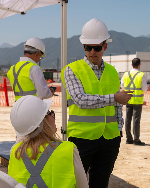 Two persons with safety equipment supervising the construction of a industrial project.