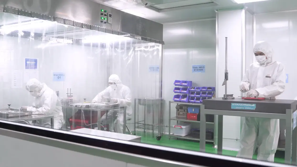 Laboratory workers in cleanroom suits using equipment.