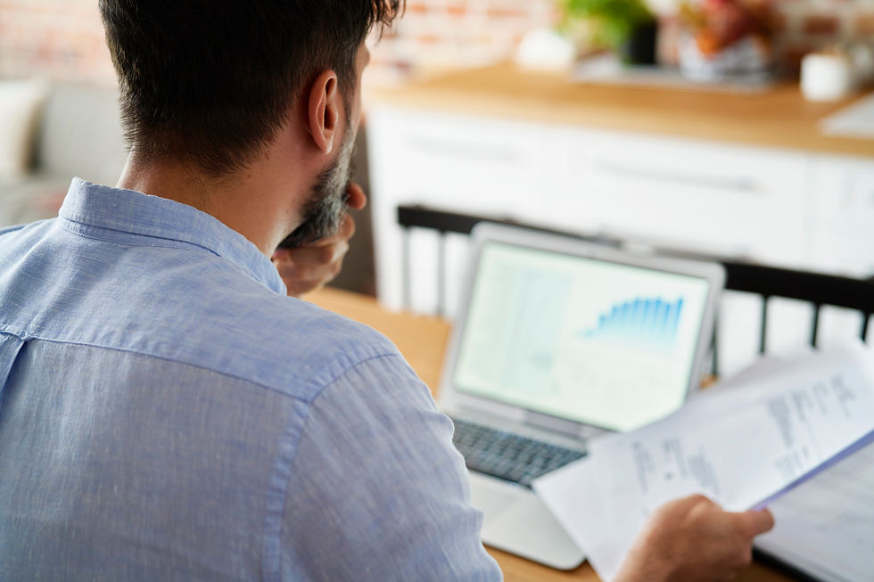 a man infront of computer reviewing bills, numbers, finances and credit scores