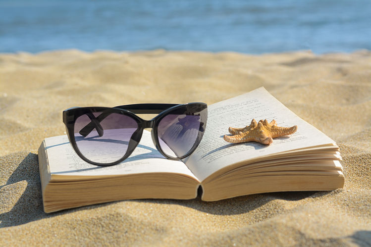 Beautiful sunglasses, book and starfish on sand near sea, closeup.jpg