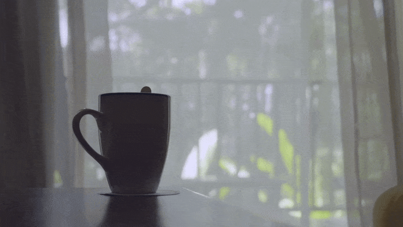 Sheer curtains blowing in a gentle breeze next to a warm cup of tea.