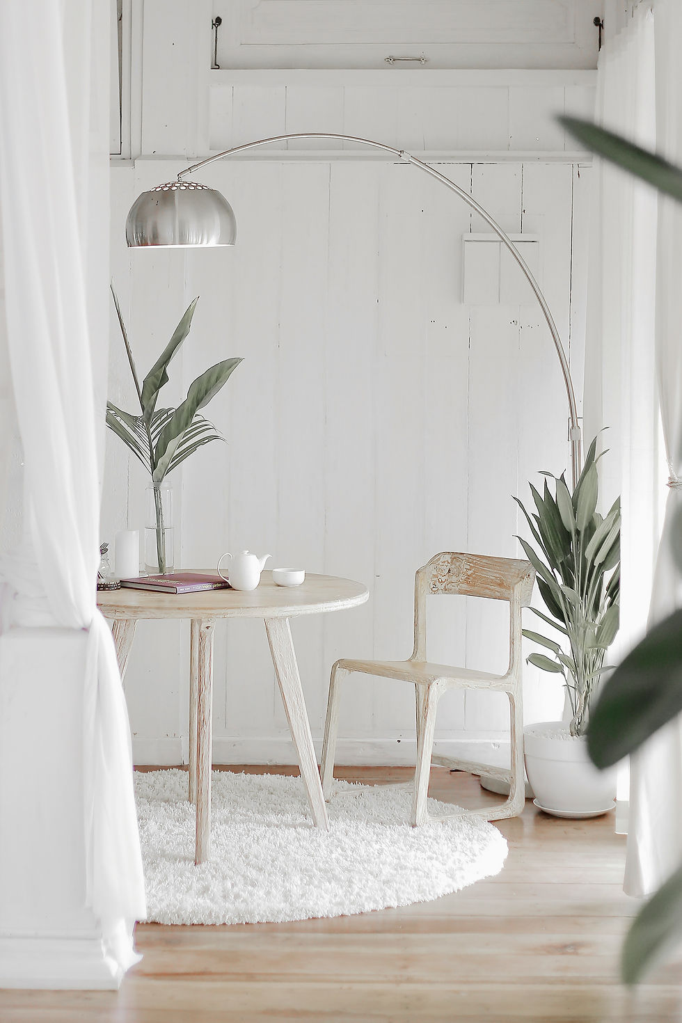 white room with a coffee table and matching wooden chairs, floor lamp