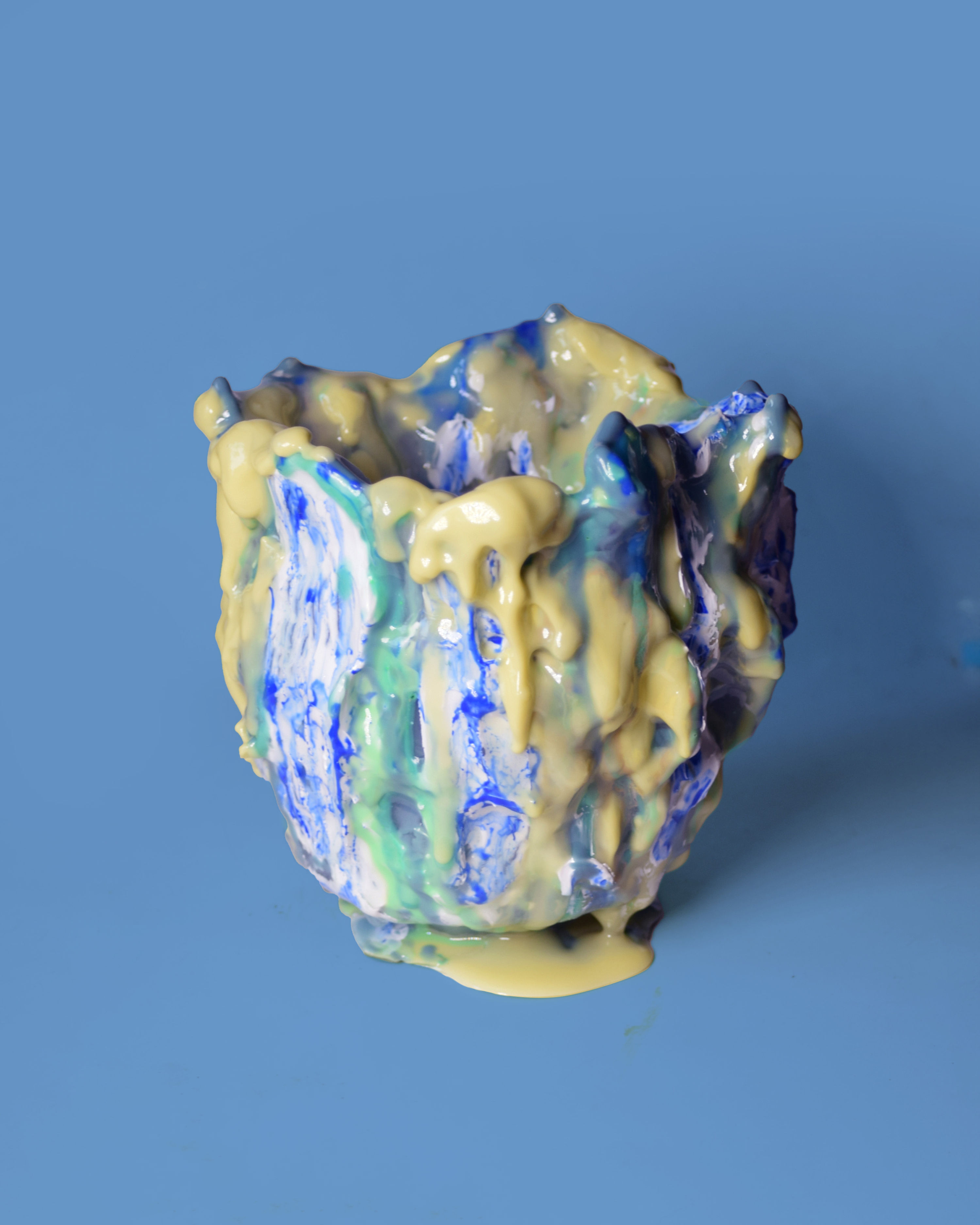 Handcrafted ceramic vase with flowing blue, green, and yellow glaze drips, sculptural organic form, contemporary art object.