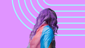 A person with purple hair wearing the trans pride flag as a cape