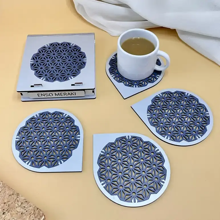 Asanoha laser cut coaster set with designer box in silver and navy blue on beige background with tea cup, angled lifestyle