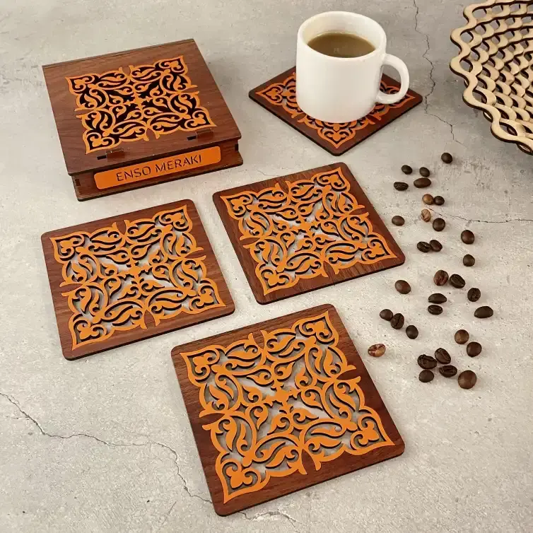 Tarini laser cut coaster set with designer box in walnut & orange with tea cup on grey backdrop, angled lifestyle image