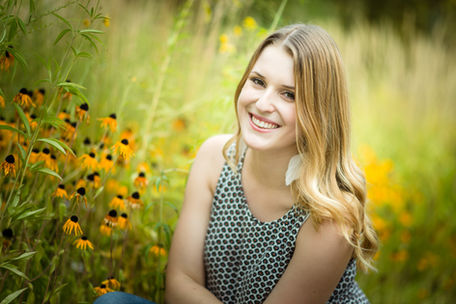 Mädchen in Blumenfeld schaut lachend in die Kamera