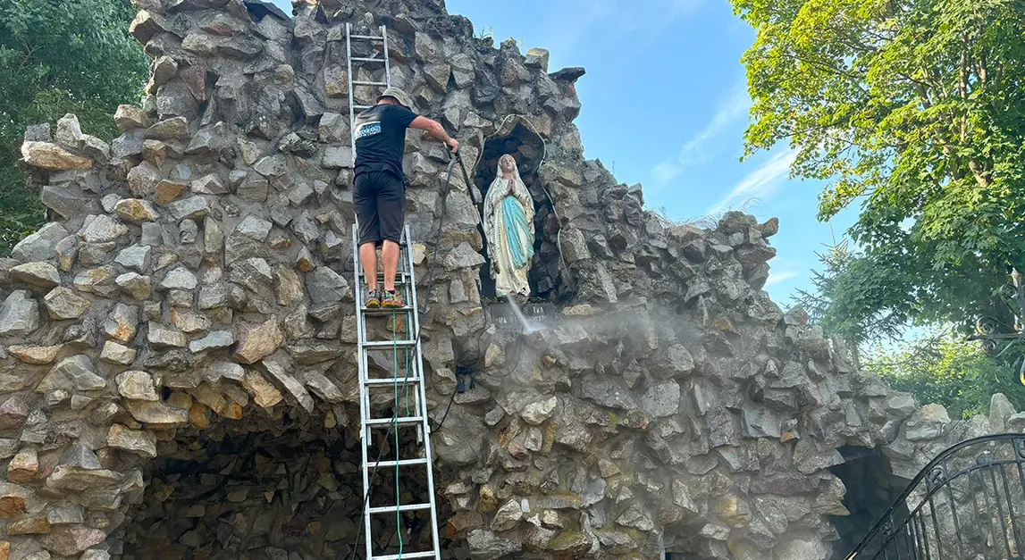 Nettoyage haute pression d’une reproduction de la grotte de Lourdes, avant traitement
