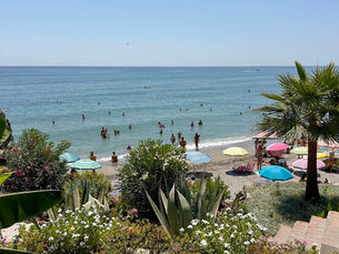 Playa El Salón en Nerja con gente tomando el sol y disfrutando de la playa en un día soleado