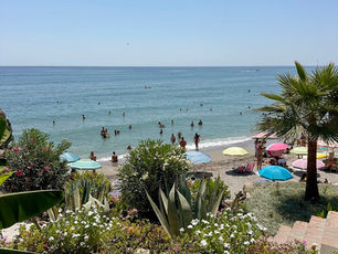 Playa El Salón en Nerja con gente tomando el sol y disfrutando de la playa en un día soleado