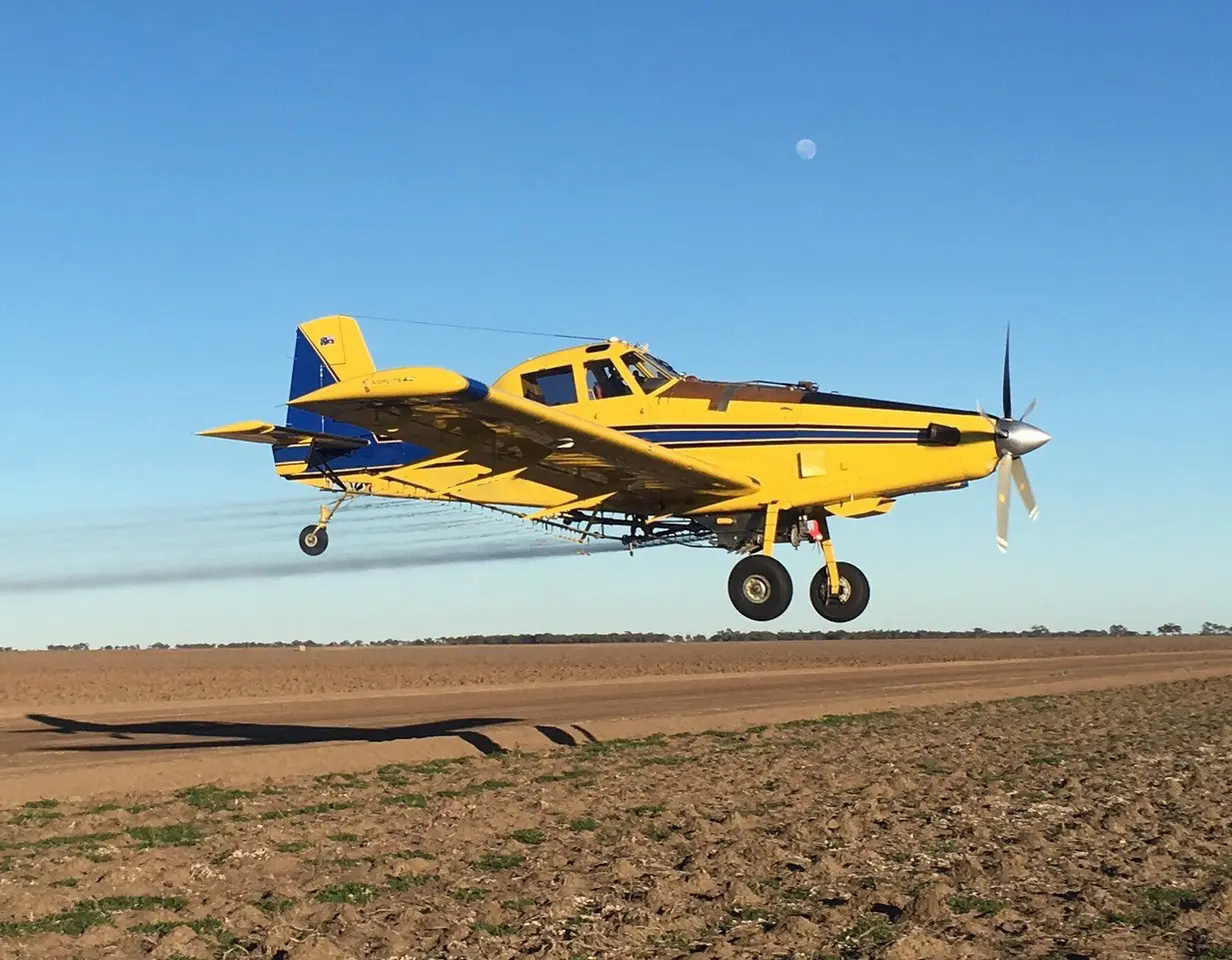 Air Tractor plane flying low and spraying a field