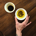 Hand holding a cup of tea with a secondary cup to the side of it