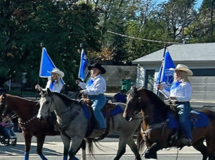 3 woman on horses holding flags at parade