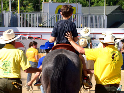 Boy on a horse with two cowboys on each side. 