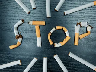 Broken cigarettes arranged to spell the word stop on wooden surface, symbolizing quitting smoking and harmful effects of tobacco use.
