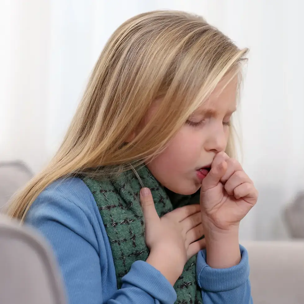 A young person with blonde hair coughs into their hand while holding their chest and wearing a blue sweater and green scarf.