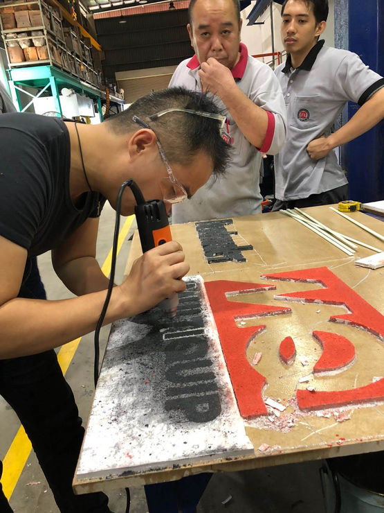 Worker using power tool to precisely cut lettering into a sign