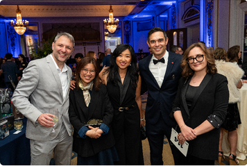 Group of guests smiling at the ESA Nite to Unite Gala during GDC 2026 in San Francisco, with blue uplighting and ballroom in the background.