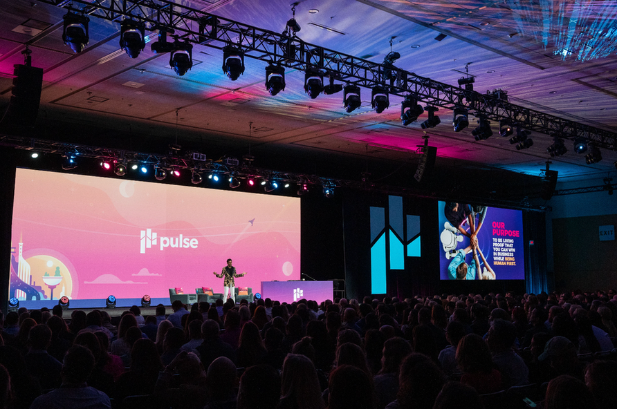 Keynote speaker on stage at a Conference at Moscone Center in San Francisco, with full audience and large branded screens, photographed by Nico Hend Photograph