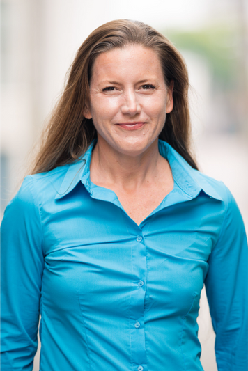 Professional headshot of a woman in a teal blazer, outdoor San Francisco location
