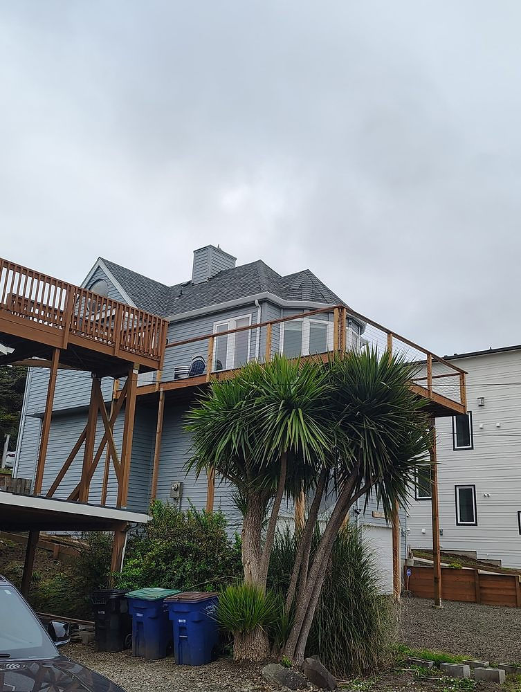 Elevated wooden deck with support beams attached to house.