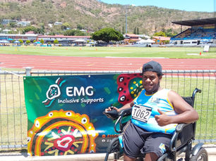 Charlie poses with the EMG Inclusive Supports Banner in Townsville