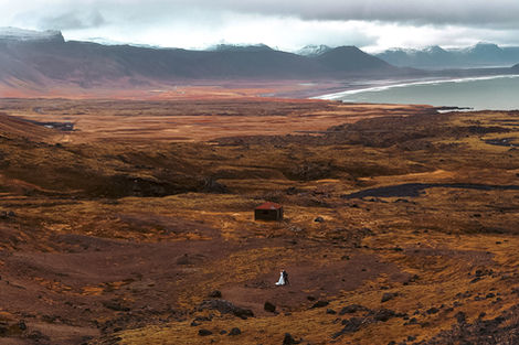 Bride and groom standing in the vast Icelandic Highlands with mountains and open landscape around them.