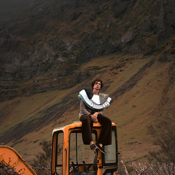 A model sitting on a yellow excavator with Icelandic landscape background 