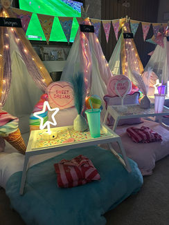Cosy indoor sleepover setup with lights and decorations.