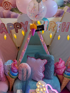 a teepee with ice cream cones and balloons and a sign that says happy birthday