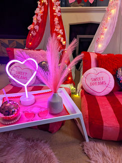 Pink cozy setup, "SWEET DREAMS" neon sign, heart pillow, pampas grass.