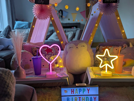 Cosy birthday setup with neon lights and decorations.